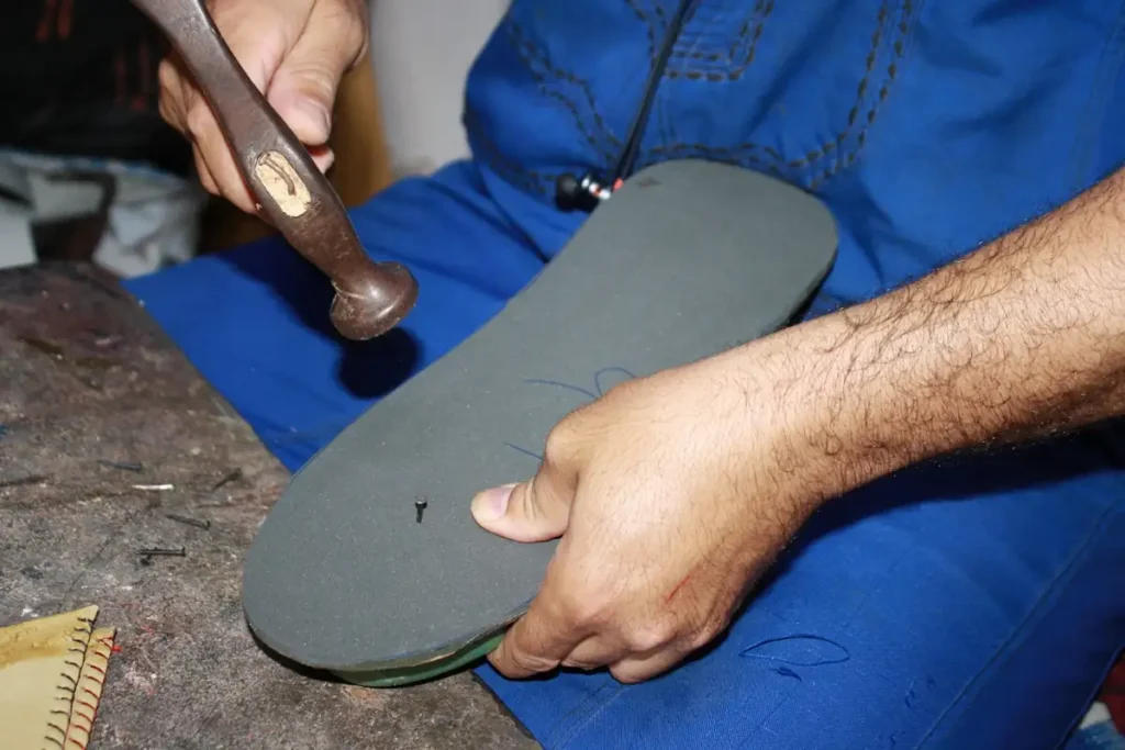 Artisan marocain clouant une semelle de babouche femme tendance – fabrication traditionnelle Bagha Shoes